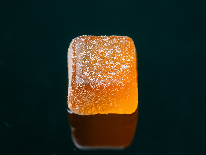 Amber cannabis gummy on dark surface, terpene-forward edible formulated with WhippedTech.